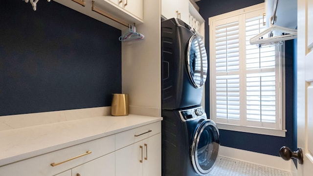 clothes washing area with stacked washer and clothes dryer and cabinet space