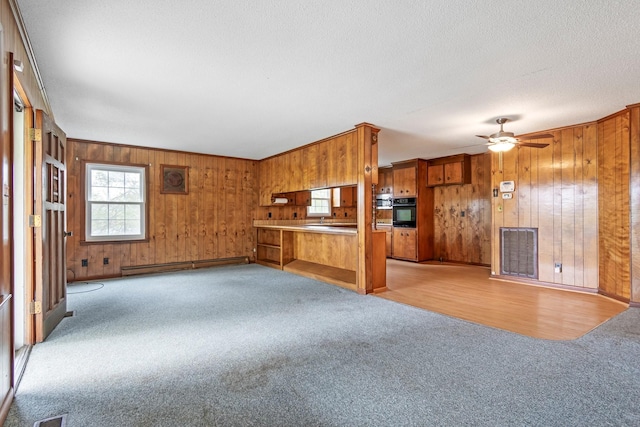 4103 Arno Rd, Franklin, TN 37064 - unfurnished living room with a baseboard radiator, ceiling fan, light carpet, wood walls, and visible vents