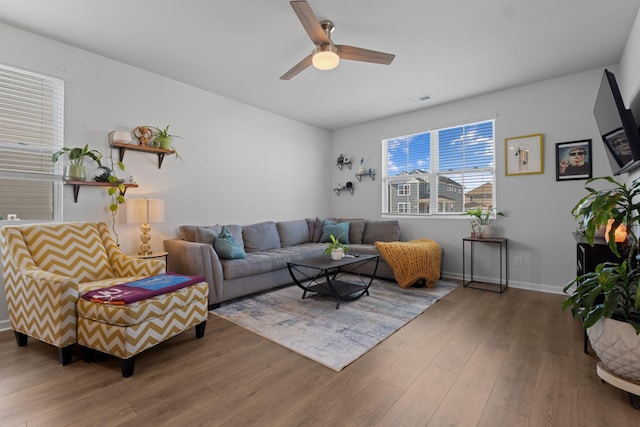 living room with wood finished floors, visible vents, a ceiling fan, and baseboards