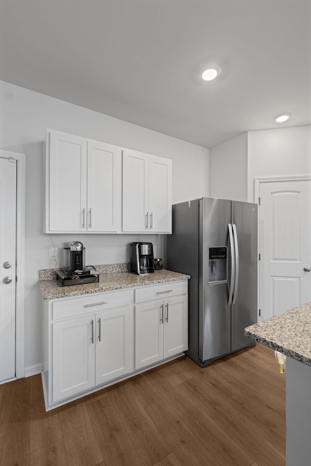 kitchen featuring light stone countertops, stainless steel refrigerator with ice dispenser, dark wood-style floors, and white cabinetry