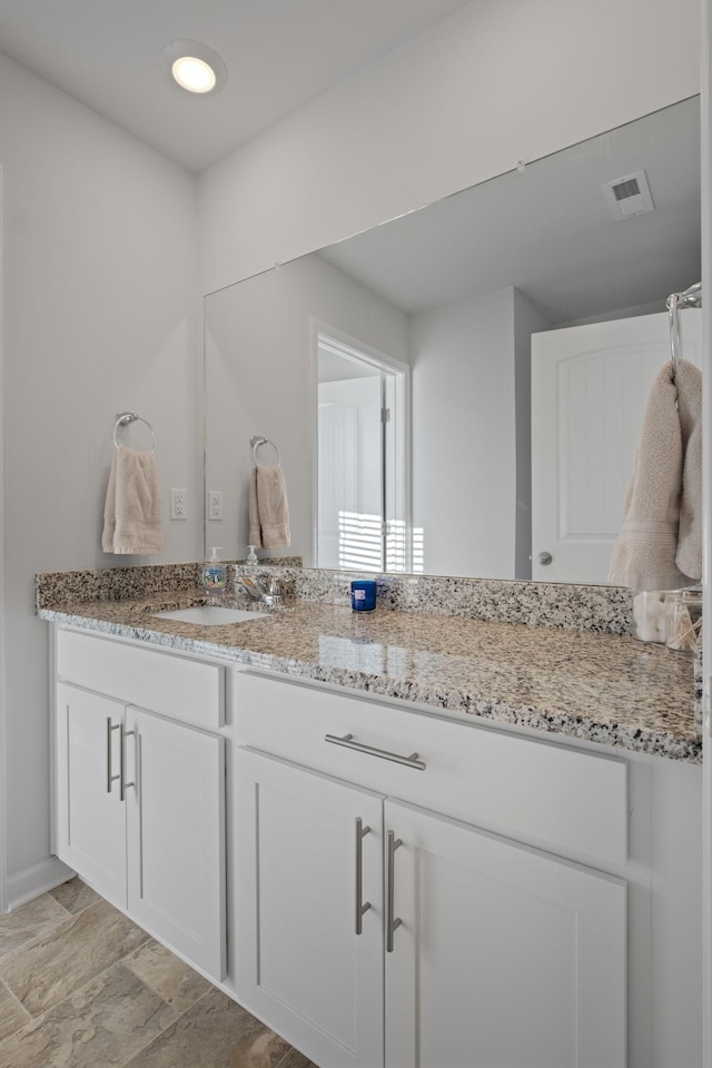 bathroom with stone finish flooring, baseboards, vanity, and visible vents
