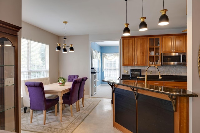 304 Hay Market Ct, Franklin, TN 37067 - kitchen with stainless steel microwave, brown cabinetry, a healthy amount of sunlight, and decorative backsplash