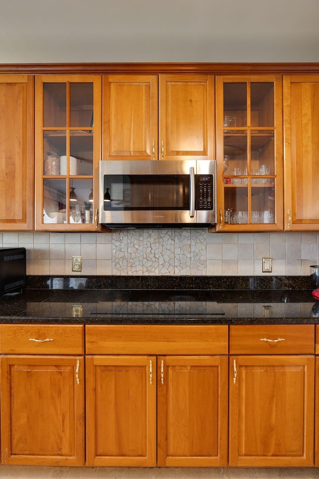 304 Hay Market Ct, Franklin, TN 37067 - kitchen with glass insert cabinets, dark stone countertops, brown cabinetry, and stainless steel microwave
