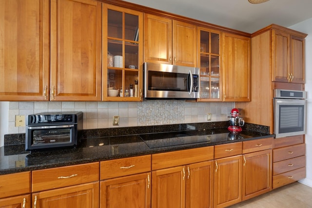 304 Hay Market Ct, Franklin, TN 37067 - kitchen with dark stone counters, backsplash, glass insert cabinets, brown cabinets, and appliances with stainless steel finishes