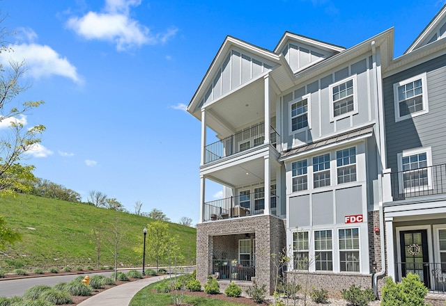 view of front of home with brick siding, a standing seam roof, a balcony, and board and batten siding