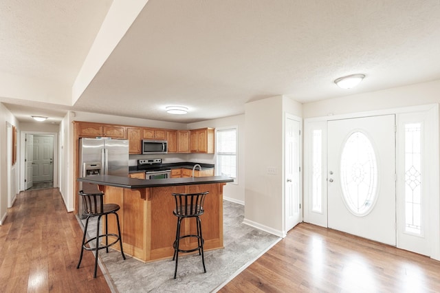 327 Arabian Ln, Springfield, TN 37172 - kitchen with dark countertops, baseboards, light wood-style flooring, appliances with stainless steel finishes, and a breakfast bar area