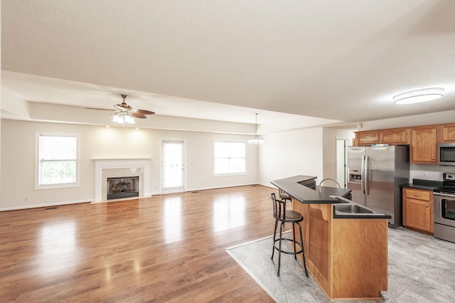 327 Arabian Ln, Springfield, TN 37172 - kitchen featuring a kitchen breakfast bar, dark countertops, light wood-type flooring, appliances with stainless steel finishes, and ceiling fan with notable chandelier