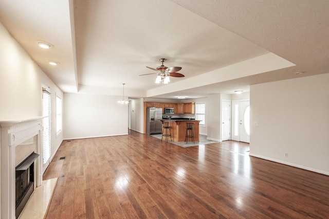 327 Arabian Ln, Springfield, TN 37172 - unfurnished living room featuring ceiling fan with notable chandelier, light wood-style floors, a wealth of natural light, a fireplace, and baseboards