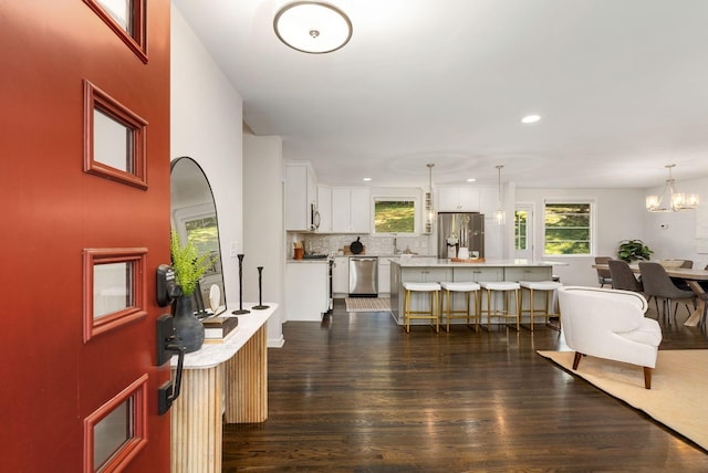 entryway with recessed lighting, dark wood finished floors, plenty of natural light, and a notable chandelier