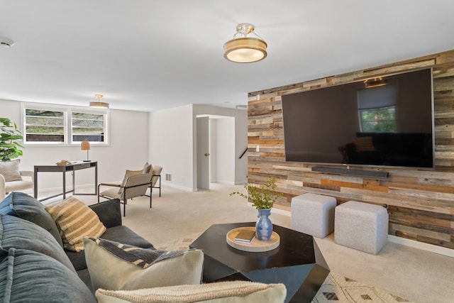 living area featuring an accent wall, wooden walls, baseboards, and carpet