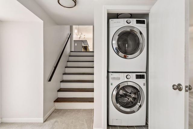 laundry room featuring baseboards, stacked washer and clothes dryer, and carpet