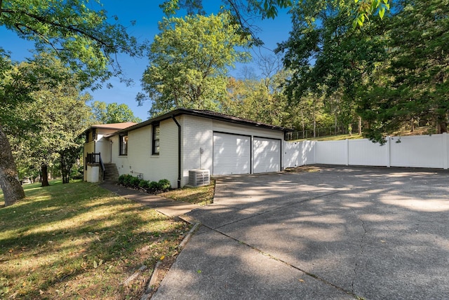 view of home's exterior with central AC, fence, a yard, a garage, and brick siding