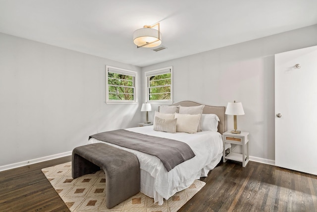 bedroom with wood finished floors, visible vents, and baseboards