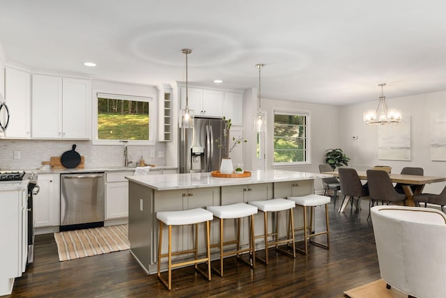 kitchen with tasteful backsplash, a healthy amount of sunlight, appliances with stainless steel finishes, and dark wood-style flooring