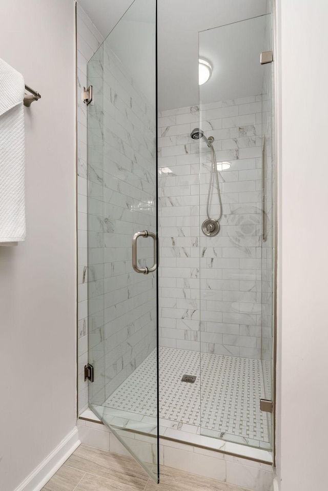 full bath with a shower stall and baseboards