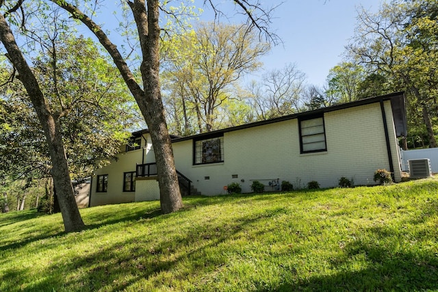 exterior space with brick siding, a yard, and central air condition unit