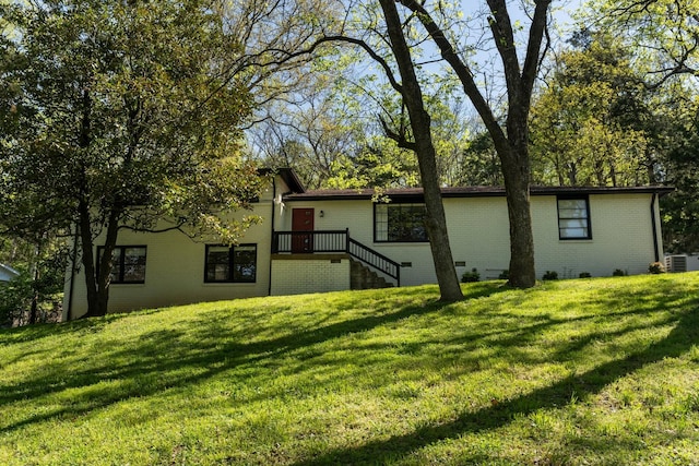 rear view of property featuring brick siding, a lawn, and central AC unit