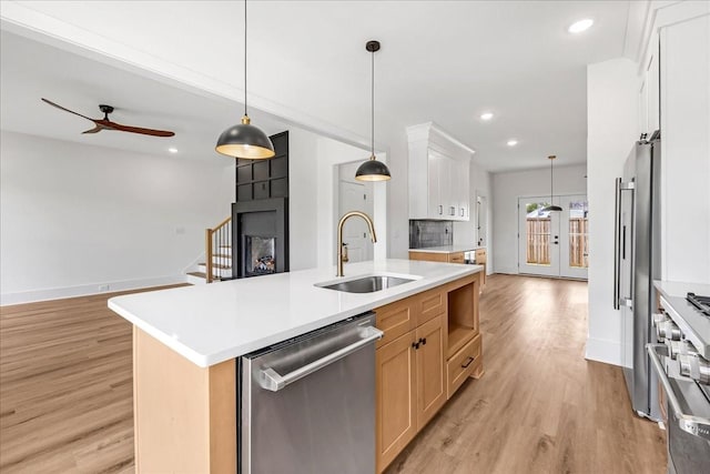 kitchen featuring a sink, open floor plan, light wood-style floors, ceiling fan, and appliances with stainless steel finishes
