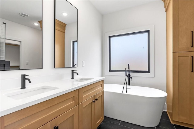 bathroom featuring tile patterned flooring, visible vents, a sink, and a freestanding bath