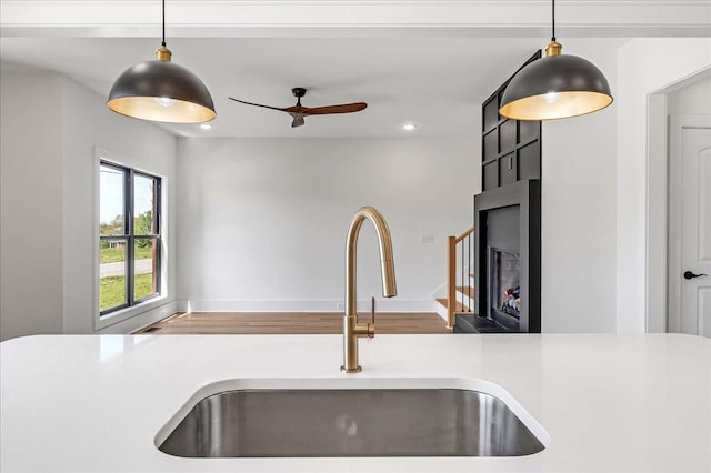 details featuring a sink, recessed lighting, a large fireplace, ceiling fan, and light countertops