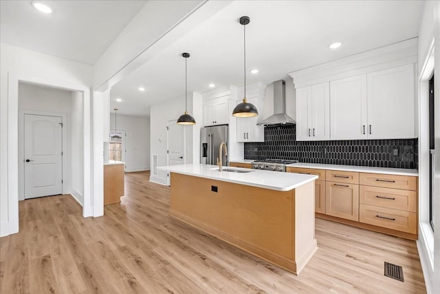 kitchen featuring a sink, stove, decorative backsplash, high end fridge, and wall chimney range hood