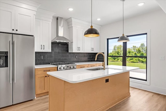 kitchen featuring a sink, light wood-style floors, stainless steel fridge with ice dispenser, wall chimney exhaust hood, and stove