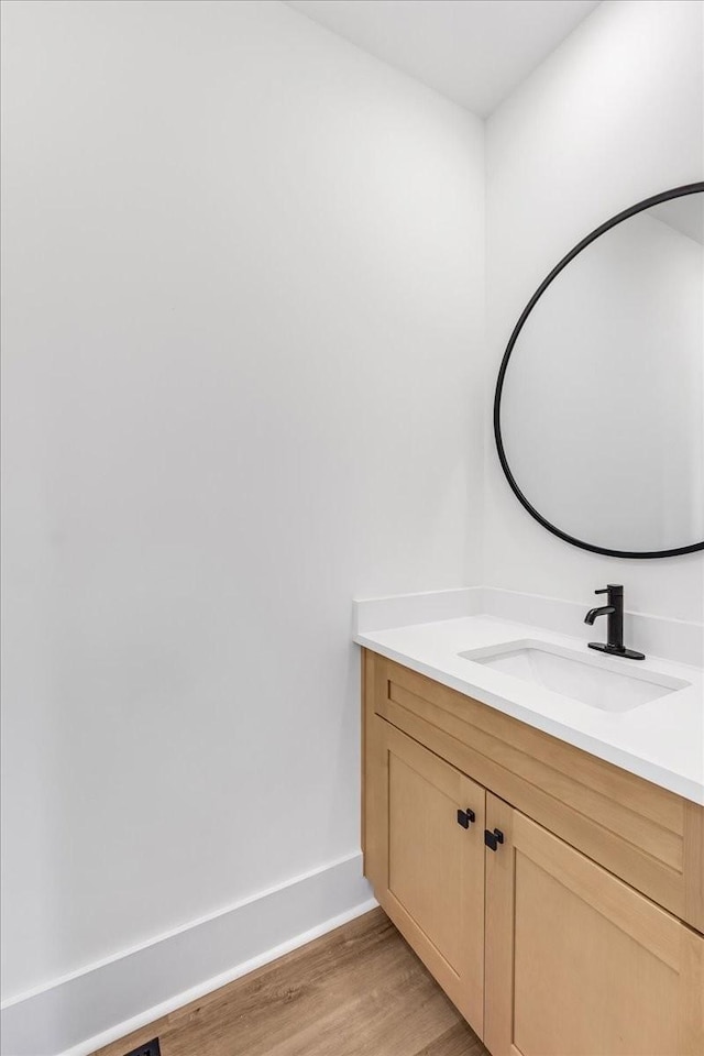 bathroom featuring baseboards, wood finished floors, and vanity