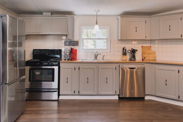 1005 Chris Dr, Portland, TN 37148 - kitchen featuring a sink, dark wood-style flooring, decorative backsplash, pendant lighting, and appliances with stainless steel finishes