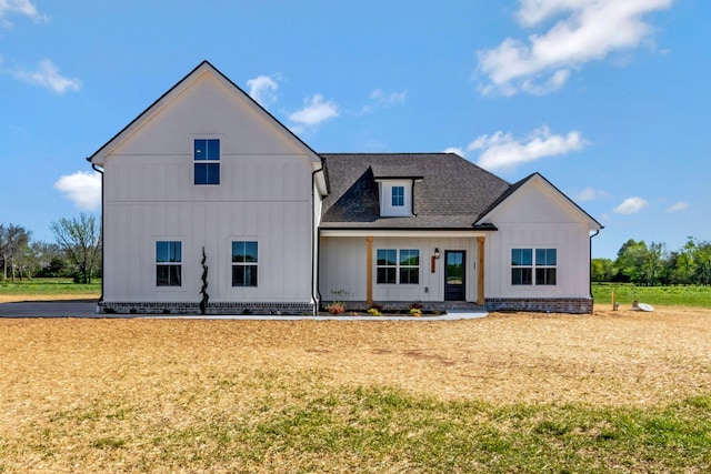 modern farmhouse style home featuring a front lawn, roof with shingles, and board and batten siding