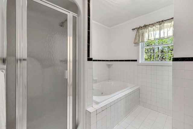 full bath with a bath, a shower stall, tile patterned flooring, and tile walls