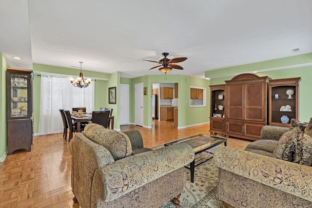 living room with baseboards and ceiling fan with notable chandelier