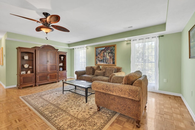 living room with a wealth of natural light, a ceiling fan, and baseboards