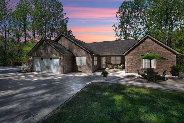view of front of property featuring concrete driveway, an attached garage, brick siding, and a front lawn