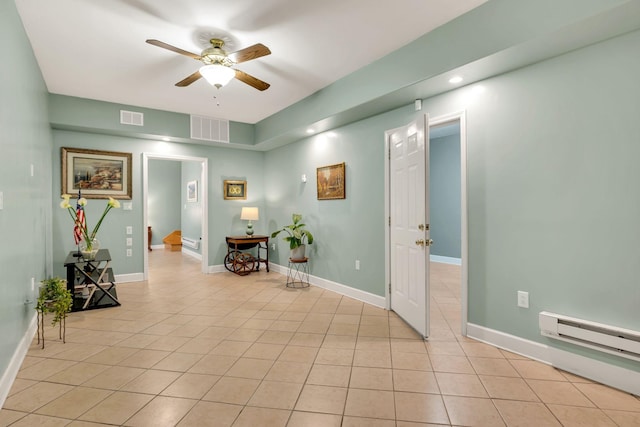 hall with a baseboard heating unit, visible vents, baseboards, and light tile patterned floors