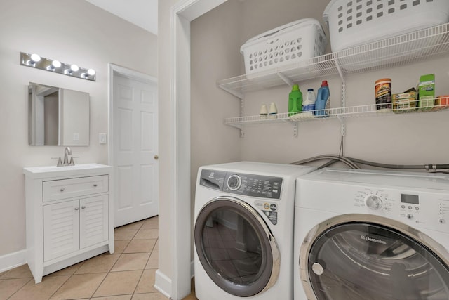 washroom featuring a sink, washer and clothes dryer, baseboards, laundry area, and light tile patterned floors