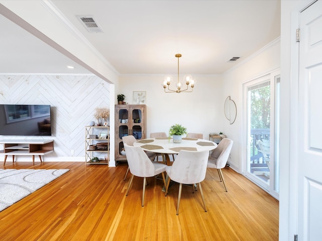 dining area featuring a chandelier, light wood-style flooring, visible vents, and ornamental molding