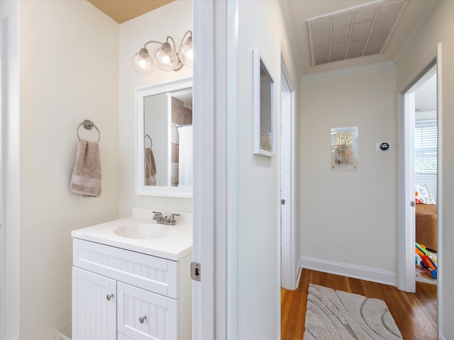 bathroom featuring visible vents, baseboards, wood finished floors, vanity, and ornamental molding