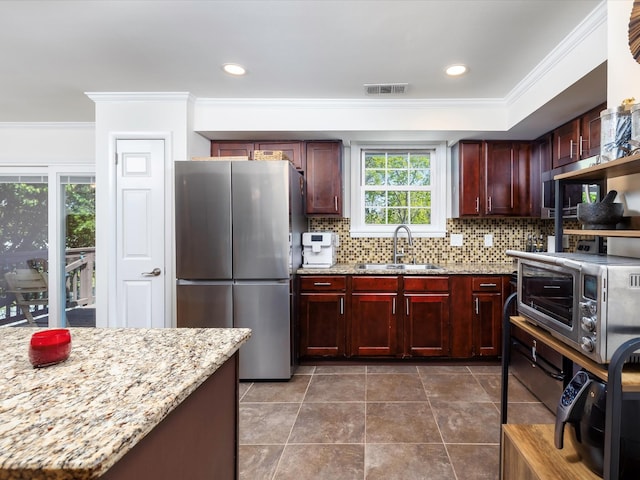 kitchen featuring freestanding refrigerator, crown molding, dark brown cabinets, and a sink