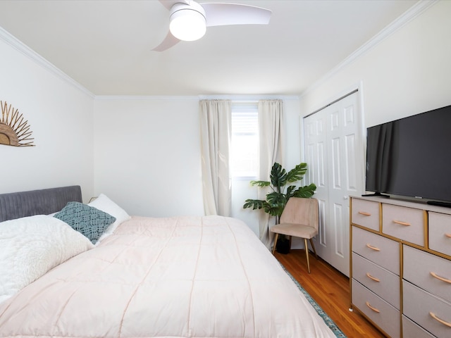 bedroom with a ceiling fan, wood finished floors, a closet, and ornamental molding