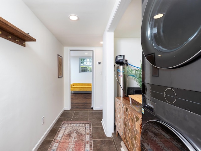 washroom featuring stacked washer / drying machine, baseboards, dark tile patterned floors, laundry area, and recessed lighting