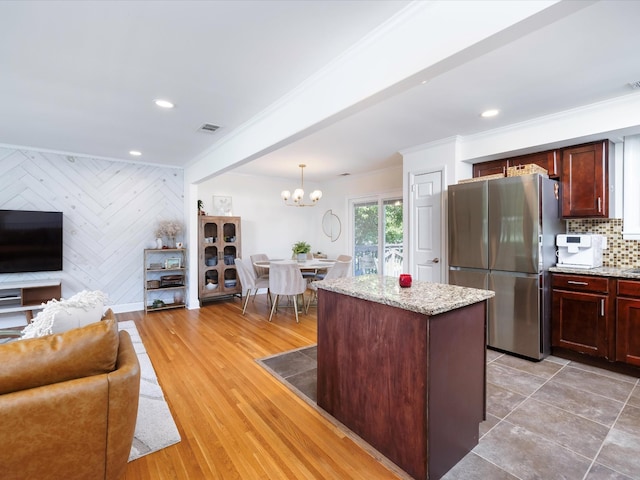 kitchen featuring open floor plan, freestanding refrigerator, a notable chandelier, and ornamental molding