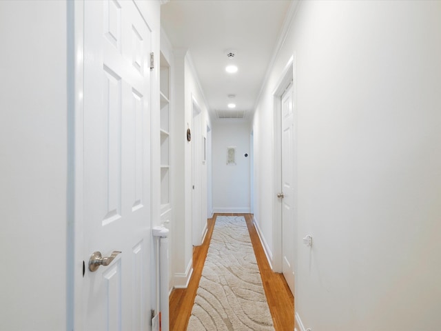 hall featuring light wood-style flooring, baseboards, and recessed lighting