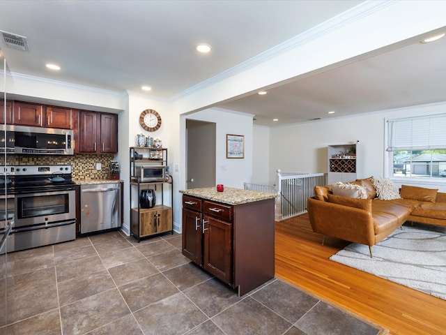 kitchen featuring stainless steel appliances, backsplash, visible vents, crown molding, and open floor plan