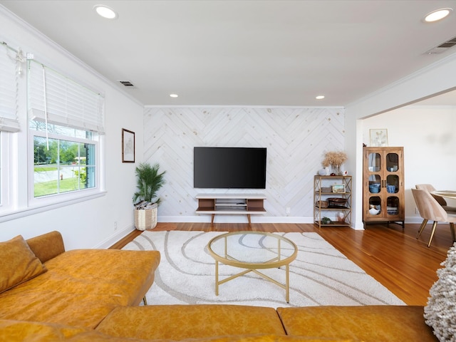 living area with baseboards, an accent wall, crown molding, and visible vents