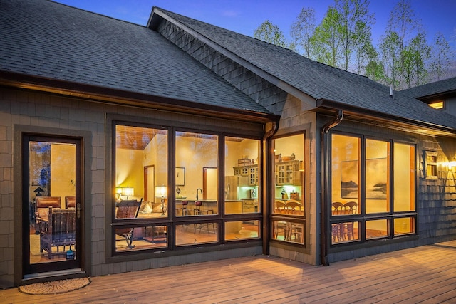 back of house featuring roof with shingles and a deck