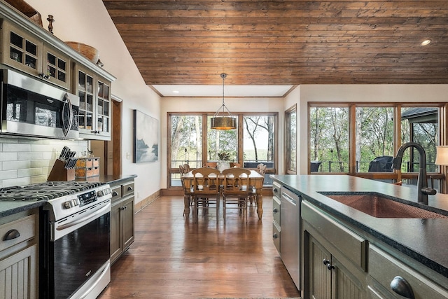 kitchen with dark countertops, tasteful backsplash, a sink, wood ceiling, and appliances with stainless steel finishes
