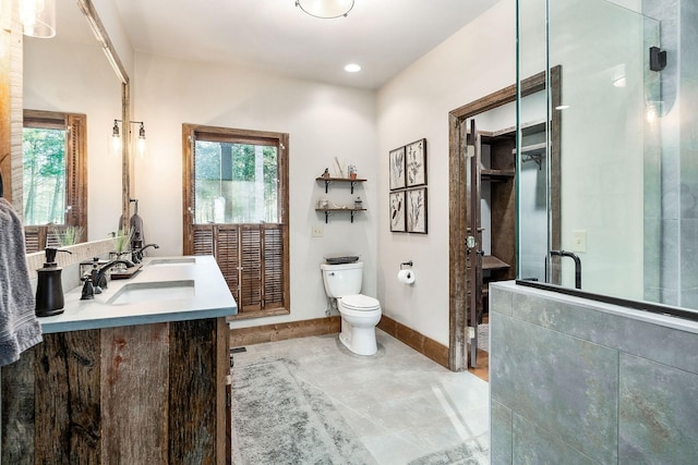 bathroom featuring a sink, double vanity, toilet, baseboards, and a shower with door