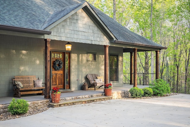 entrance to property featuring a porch and roof with shingles