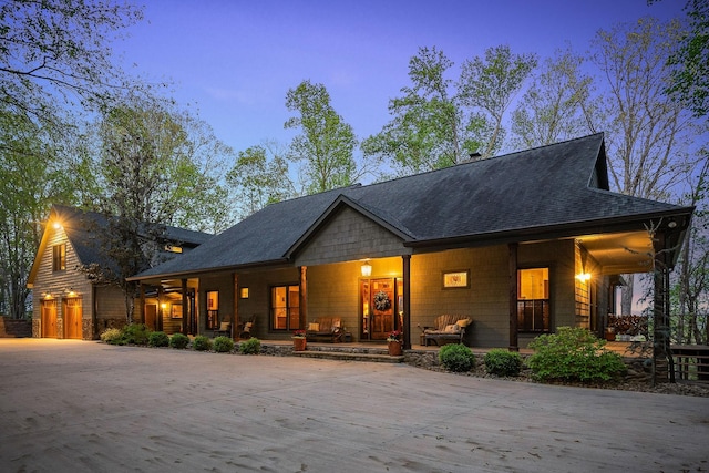 view of front facade featuring a shingled roof, concrete driveway, and covered porch