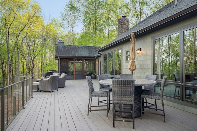 wooden terrace with outdoor dining area and a sunroom
